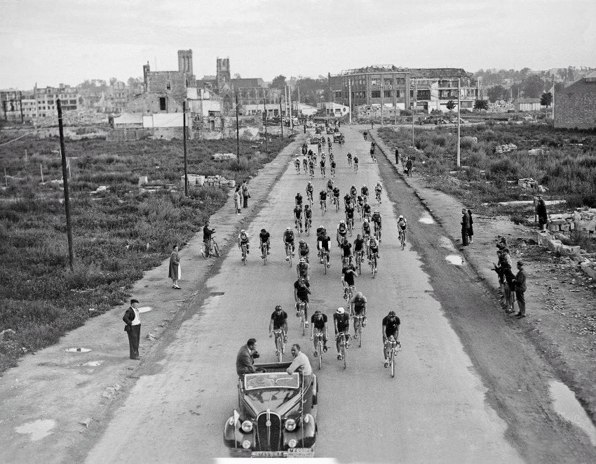 1947: The Tour de France resumed two years after the World War II. In the photo above, you can see the riders leaving the town of Caen. Damage to the buildings is still visible.