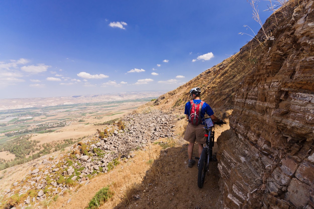 Israel. A cyclist moves his mountain bike through a narrow trail on a mountainside in the Galilee.